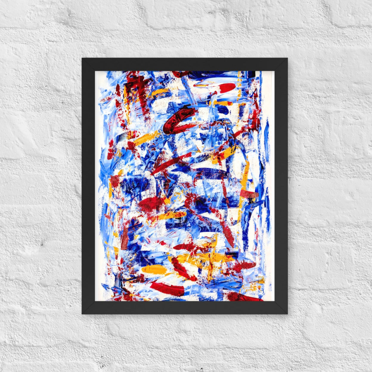 Framed abstract print titled "Rebel Parade" featuring bold red, blue, and white brushstrokes, displayed on a white brick wall in a modern interior setting.