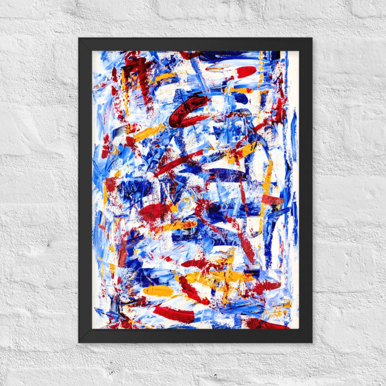 Framed abstract print titled "Rebel Parade" featuring bold red, blue, and white brushstrokes, displayed on a white brick wall in a modern interior setting.