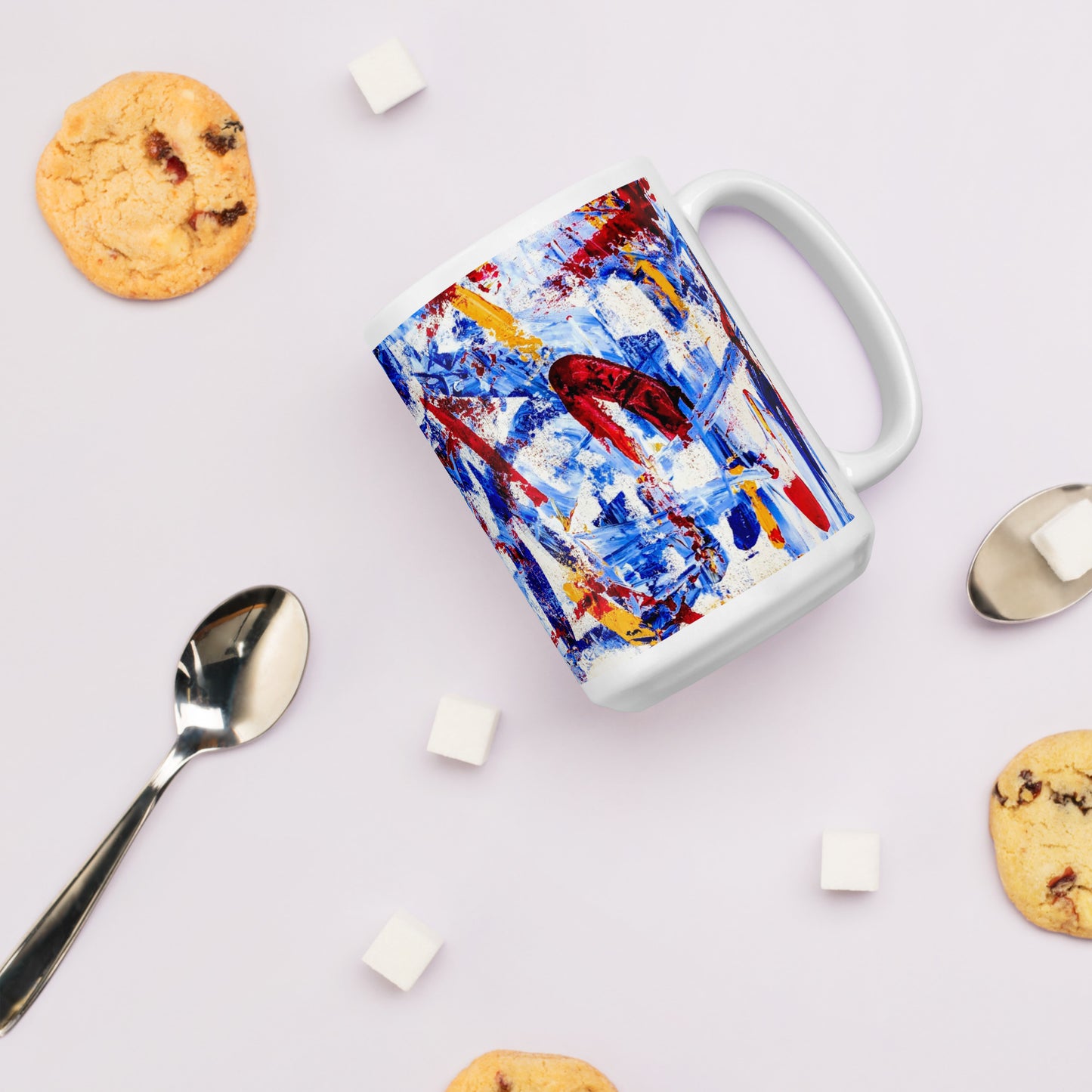 Ceramic mug featuring the abstract artwork "Rebel Parade" with bold red, blue, and white brushstrokes wrapping around the surface, shown with cookies and marshmallows