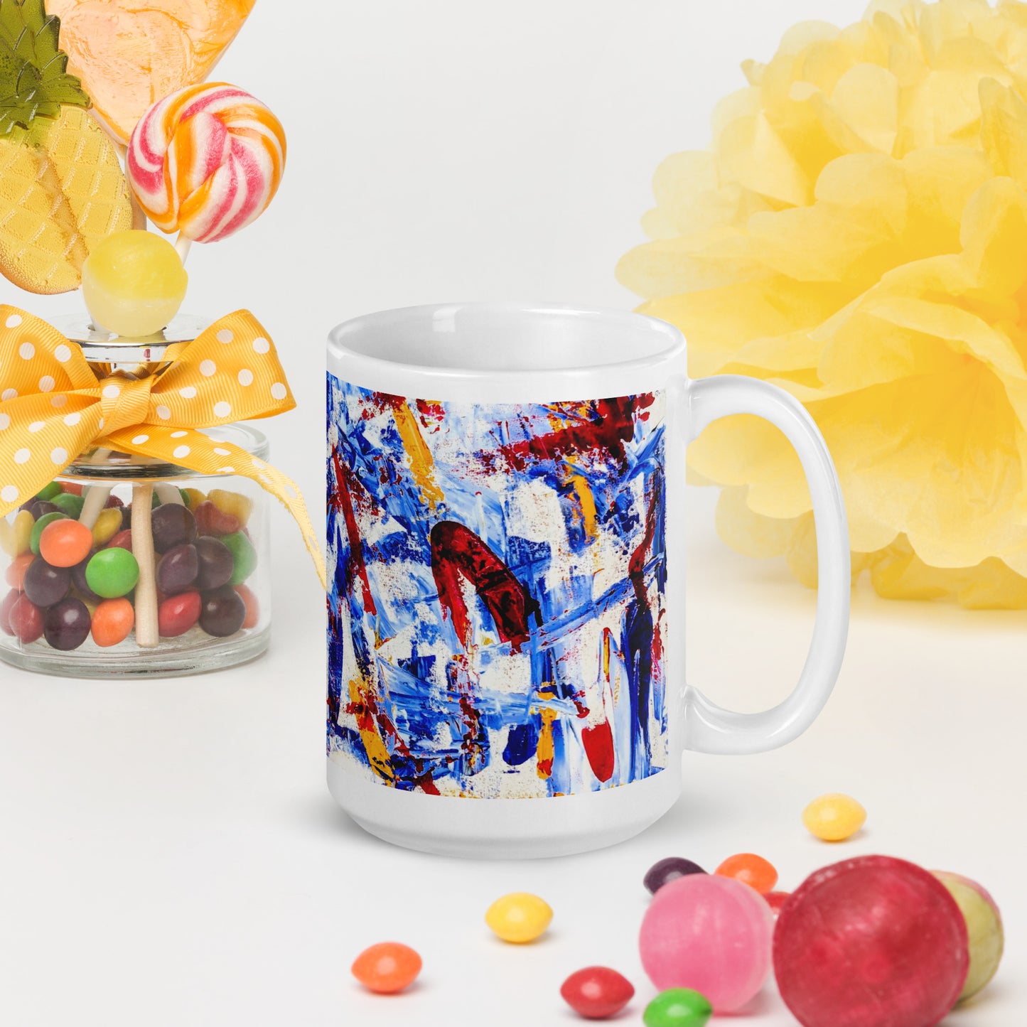 Ceramic mug featuring the abstract artwork "Rebel Parade" with bold red, blue, and white brushstrokes wrapping around the surface, shown with candy jars and candy