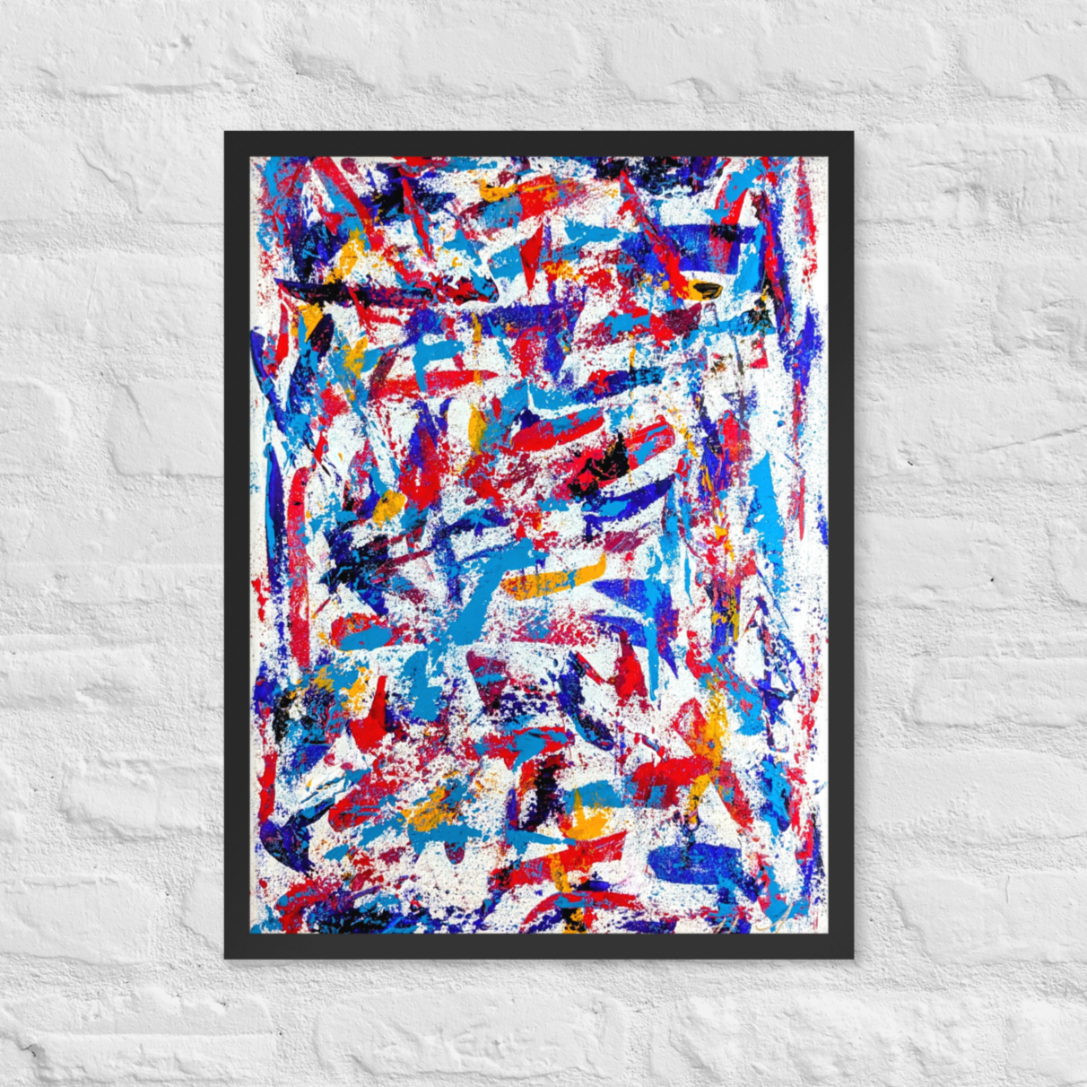 Framed abstract artwork with red, blue, and yellow colors on a white brick wall.